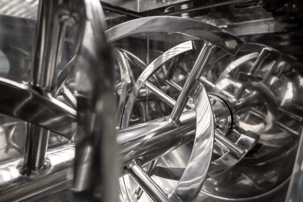 Stainless steel paddle blades inside an industrial powder mixer machine, ideal for tumbling and polymer mixing processes.